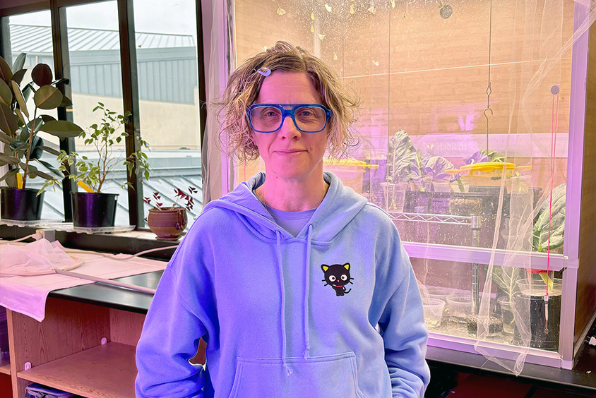 Dr. Gwen Shlichta poses in front of the butterfly cage