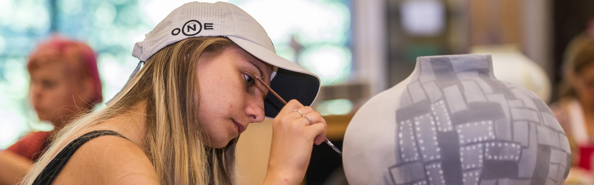 Student painting a jug