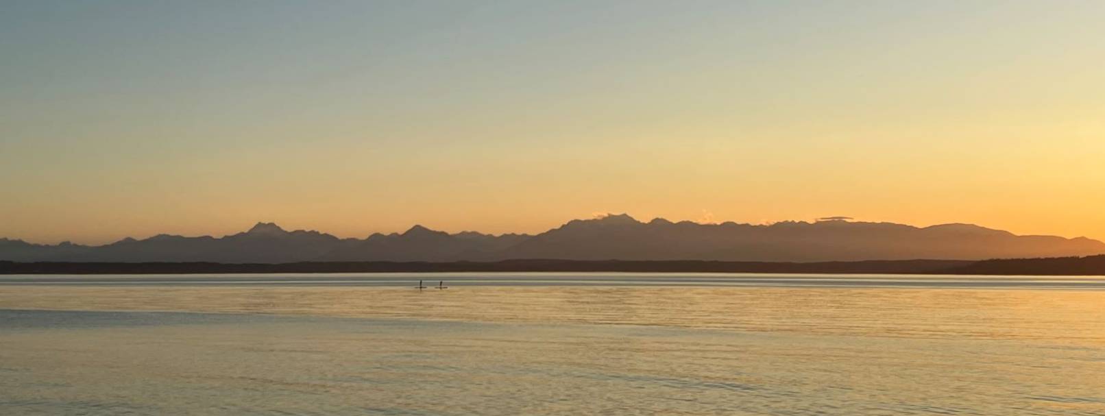 two paddleboards on the water at sunset with mountains in the background